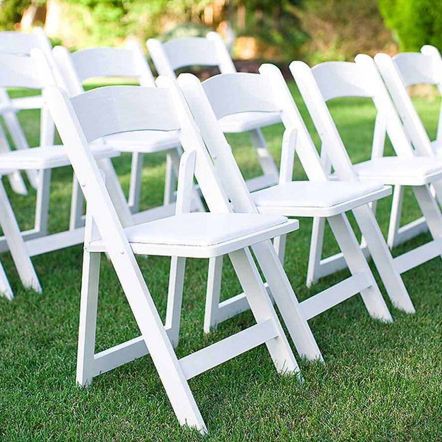 Silla plegable de resina blanca con asiento acolchado en un parque